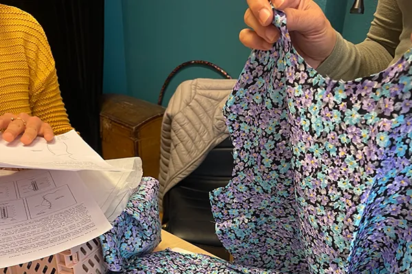 Main qui tient un tissu avec motif floral.