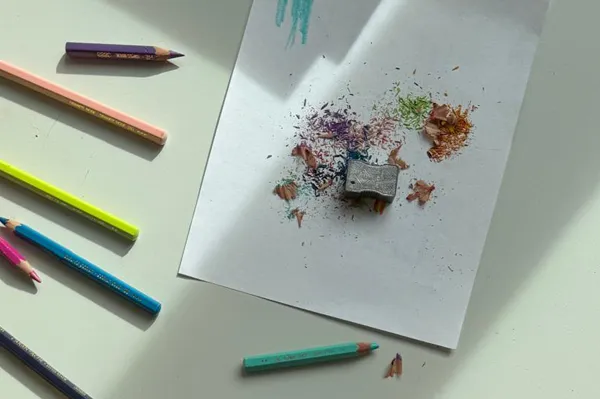 Feuille de papier avec taille crayon posé dessus et quelques crayons de couleur